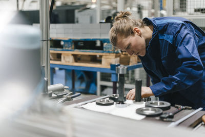 Young woman working as a skilled worker in a high tech company, controlling production machine