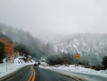 Road amidst trees against sky during winter