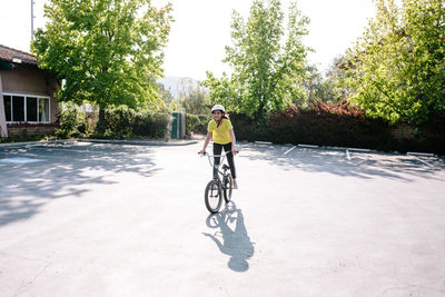 Tween girl stands on the pedals of her bike while smiling