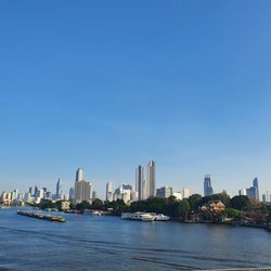 Sea and buildings against clear blue sky