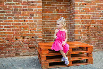 Portrait of young woman standing against brick wall