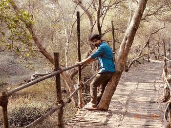 Side view of young man on bare tree