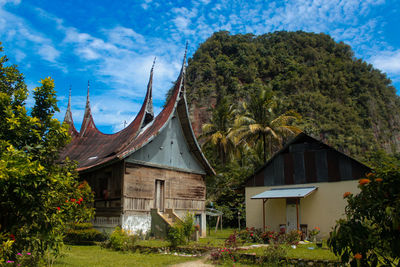 House amidst trees and buildings against blue sky