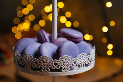 Lilac macaroons on a dessert stand. in the background, a bokeh effect from the yellow lights.