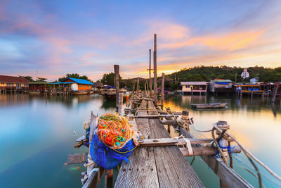 Boats moored in river against sky during sunset