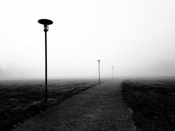 Street light on misty road against sky