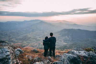 Rear view of man looking at mountains against sky