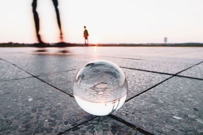 Close-up of crystal ball on water surface against clear sky