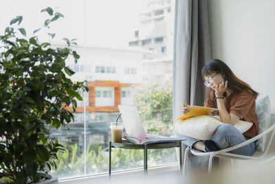 Woman looking at camera while sitting in laptop