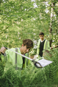 Teenage boy picking plastic garbage from plant