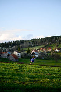 Scenic view of agricultural field by houses against sky
