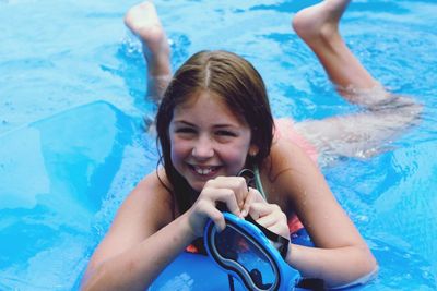 High angle portrait of smiling young woman swimming in pool