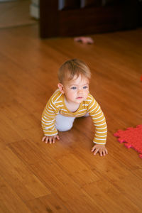 High angle view of cute baby boy on hardwood floor at home