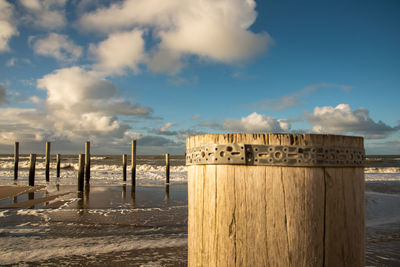 Wooden posts on beach against sky