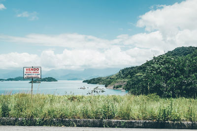 Information sign at lakeshore against cloudy sky