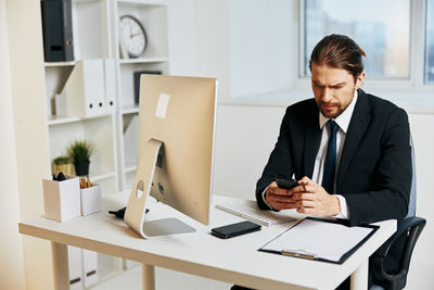 Mid adult man using mobile phone at table