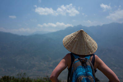 Rear view of backpacker wearing asian style conical hat looking at view