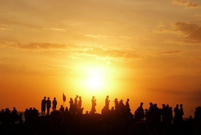 Silhouette people at beach against sky during sunset