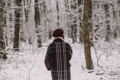 Rear view of man walking on snow covered landscape