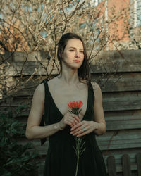 Portrait of young woman standing against wall