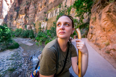 Portrait of young woman standing on rock by river