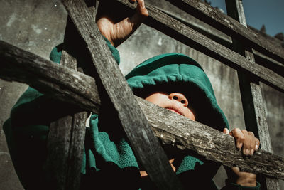 Low angle portrait of boy in hood standing at railing
