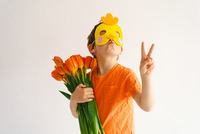 Boy showing peace sign holding bouquet