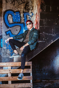 Portrait of young man sitting on wall