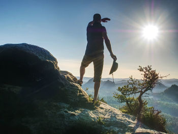 Hiker girl with leather cap stay with hands in pocket on cliff edge above valley. marvelous autumn