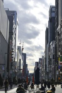 People walking on city street against buildings