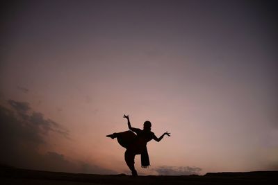 Low angle view of silhouette man standing against sky during sunset