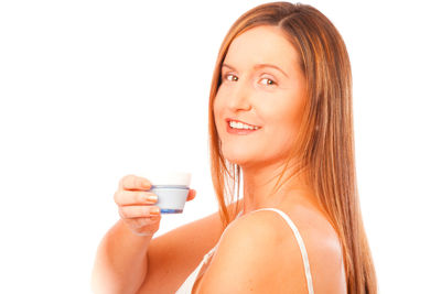Portrait of young woman drinking water against white background