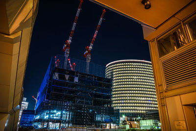 Low angle view of illuminated buildings against sky at night