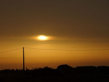 Silhouette pole on field against orange sky