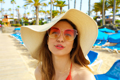 Portrait of young woman wearing sunglasses and hat at beach