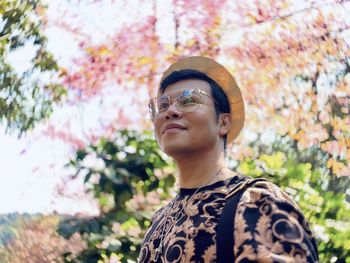 Portrait of man looking away against trees