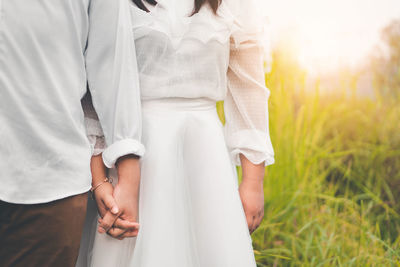 Midsection of couple holding hands outdoors