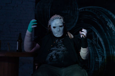 Man wearing halloween costumer sitting at table in darkroom
