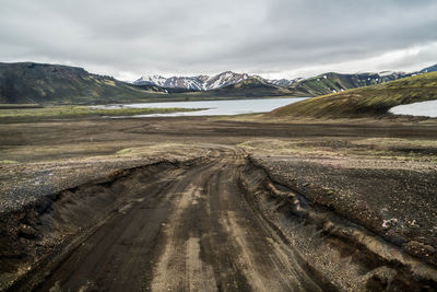 Road leading towards mountains against sky