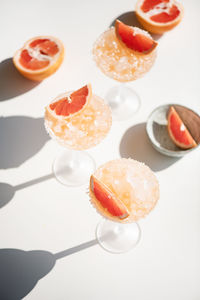 Pink grapefruit margarita cocktails on white background with shadows