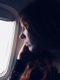 Close-up of thoughtful woman looking through airplane window