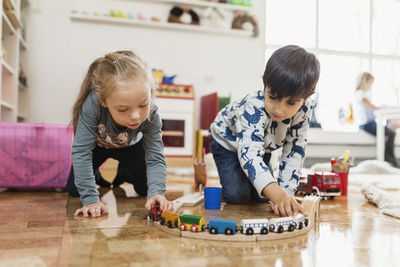 Little boy and girl playing with toy train at preschool