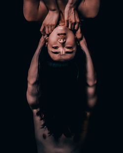 Midsection of shirtless young woman standing against black background