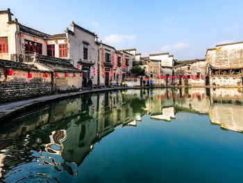 Arch bridge over river by buildings against sky