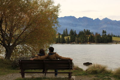 Man sitting on bench by lake