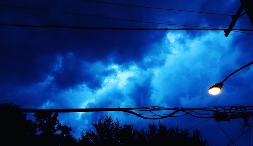 Low angle view of electricity pylon against cloudy sky