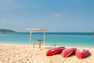 Deck chairs on beach against sky