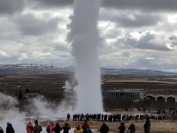 People at observation point against cloudy sky
