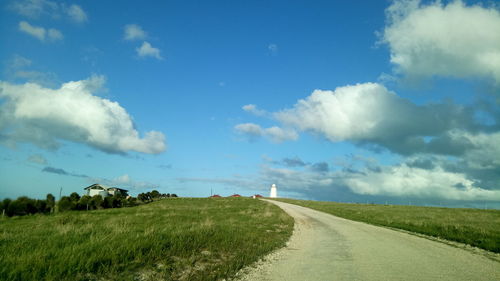 Road amidst field against sky
