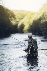 Rear view of man fishing in lake